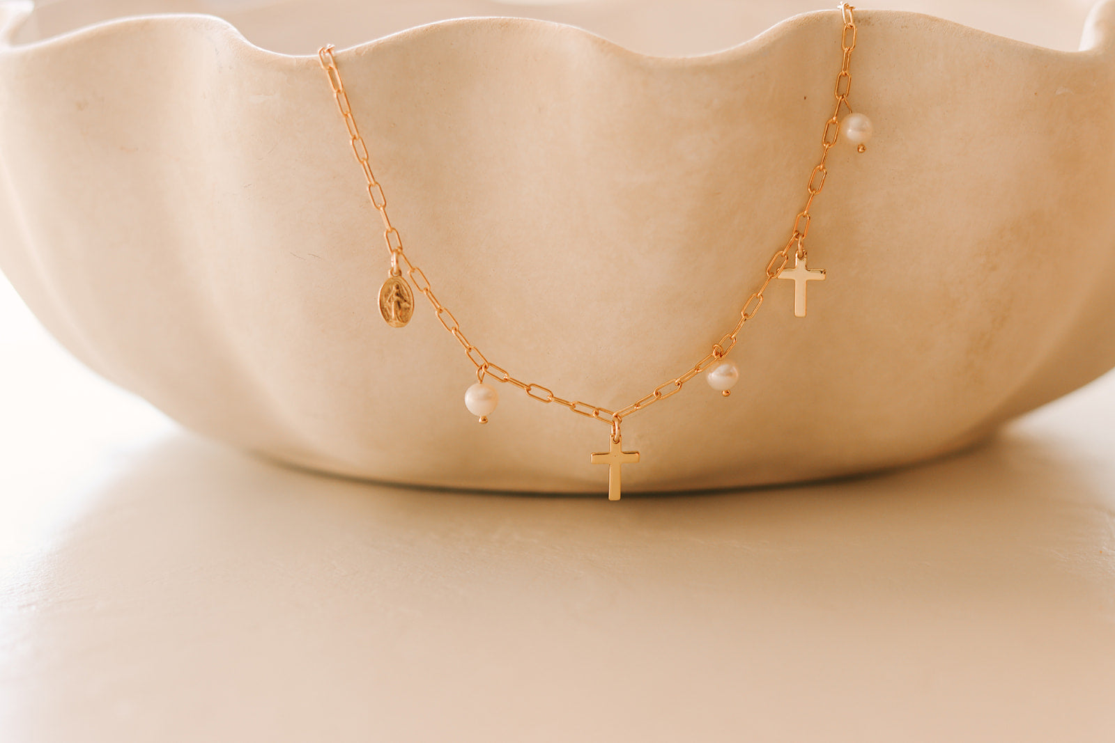 Gold cross charm necklace with pearl drops and round disc accent