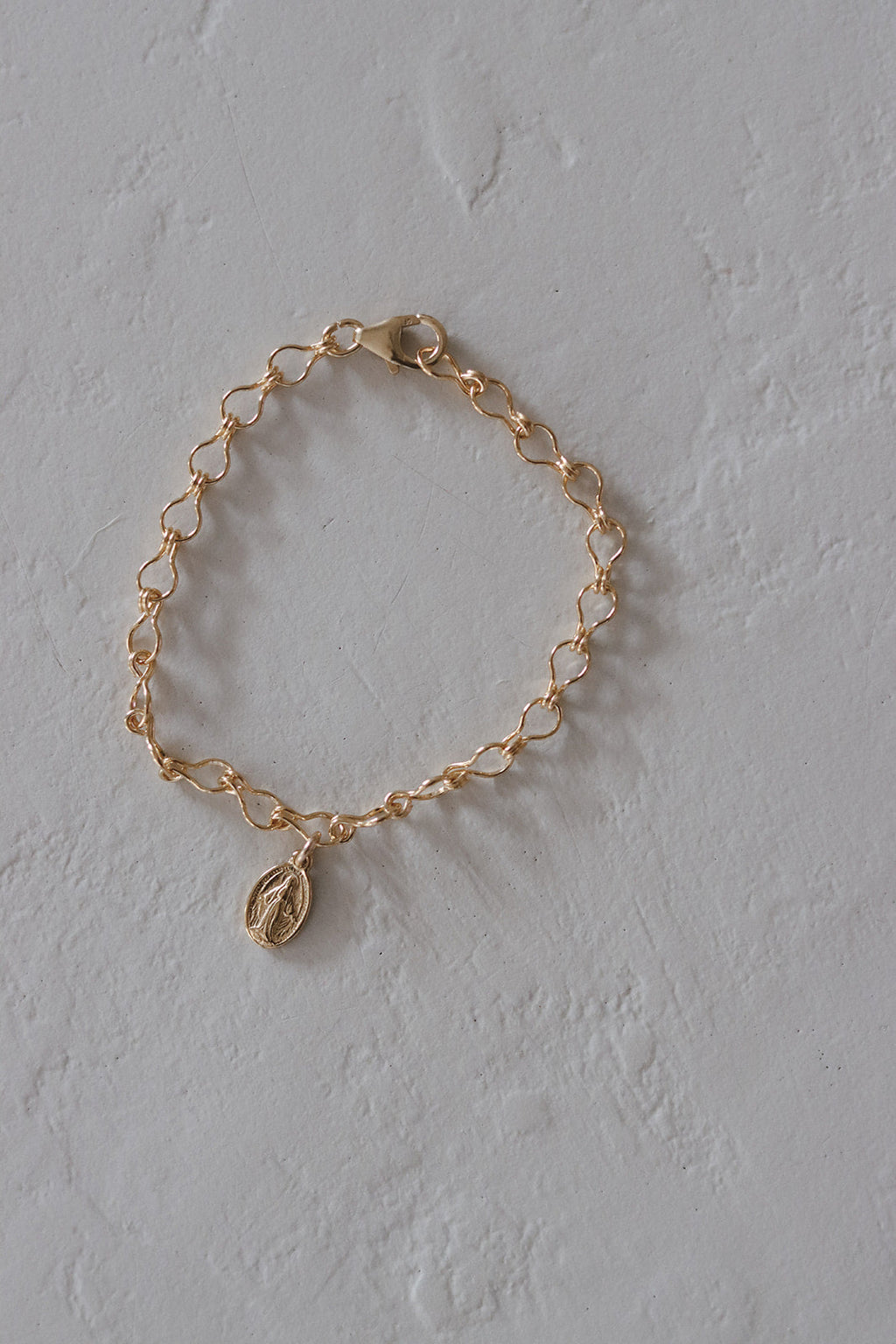 Gold-tone linked bracelet with small oval medal charm