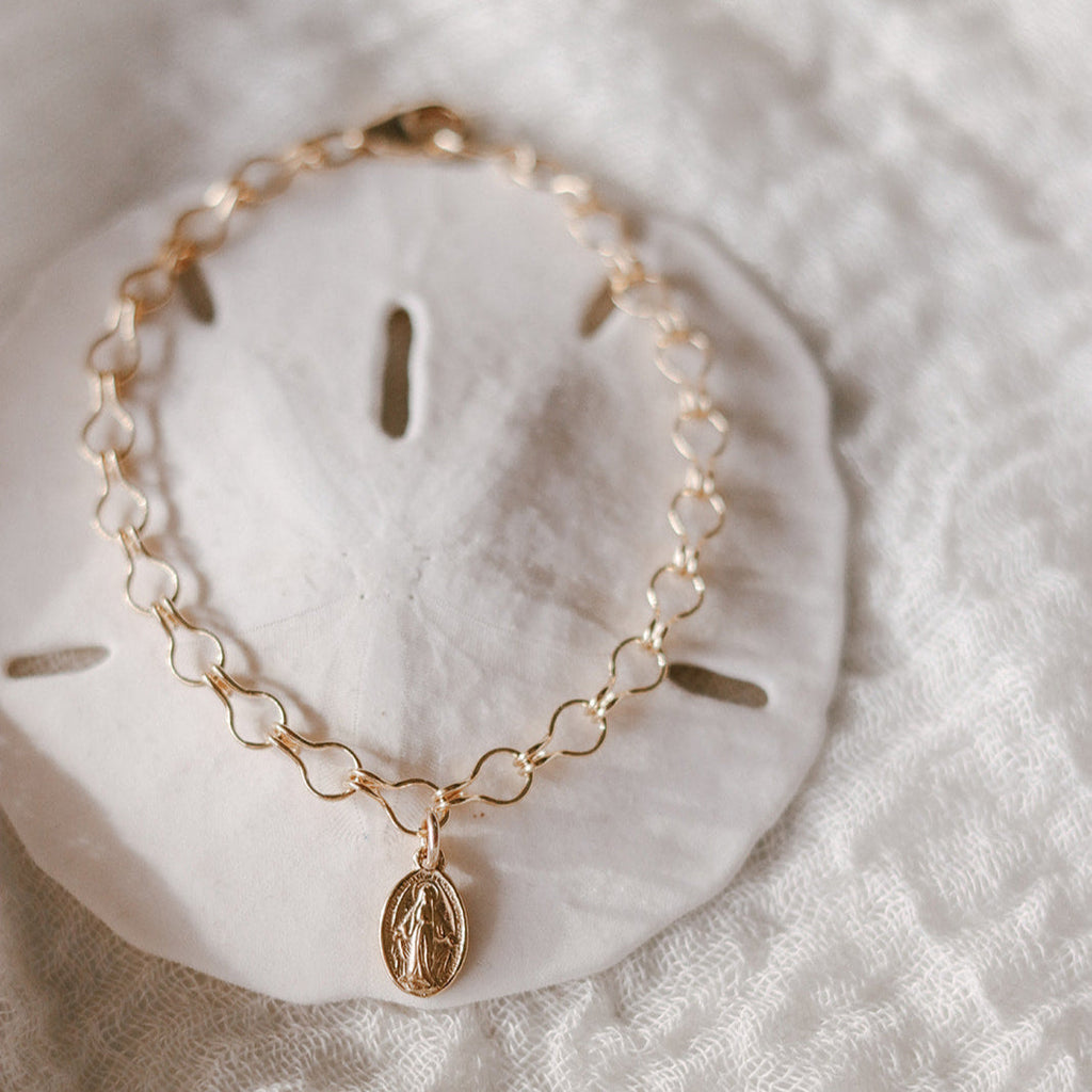 Gold-tone chain bracelet with small oval medal charm and oval clasp link detail