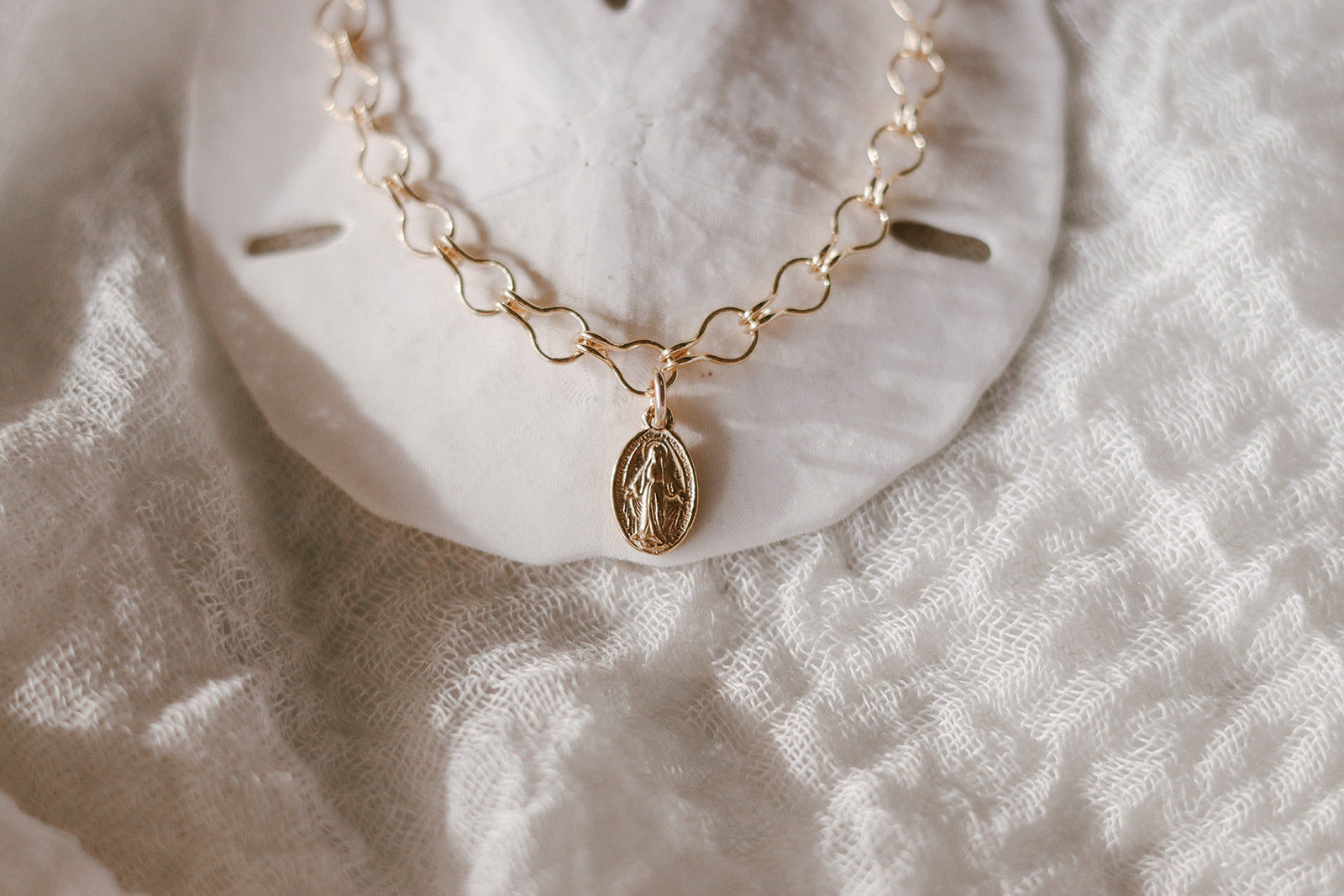 Gold-tone bracelet with oval medal charm centered on a linked chain