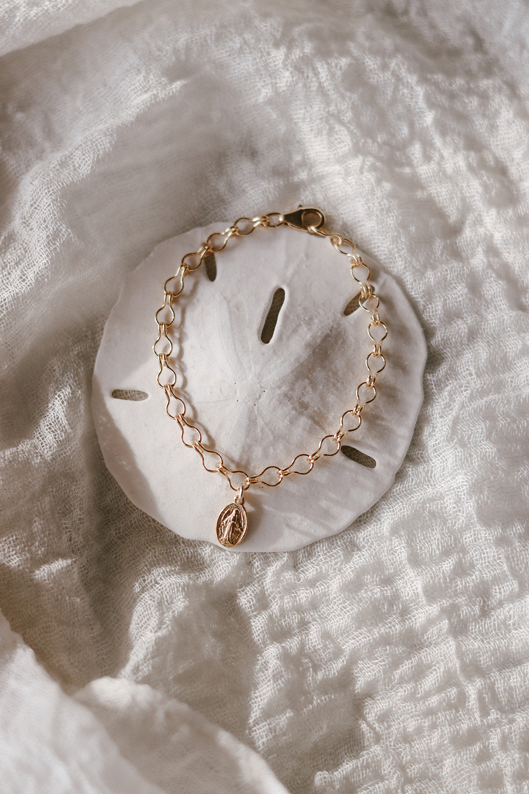 Gold-tone bracelet with oval medal charm and linked chain profile view