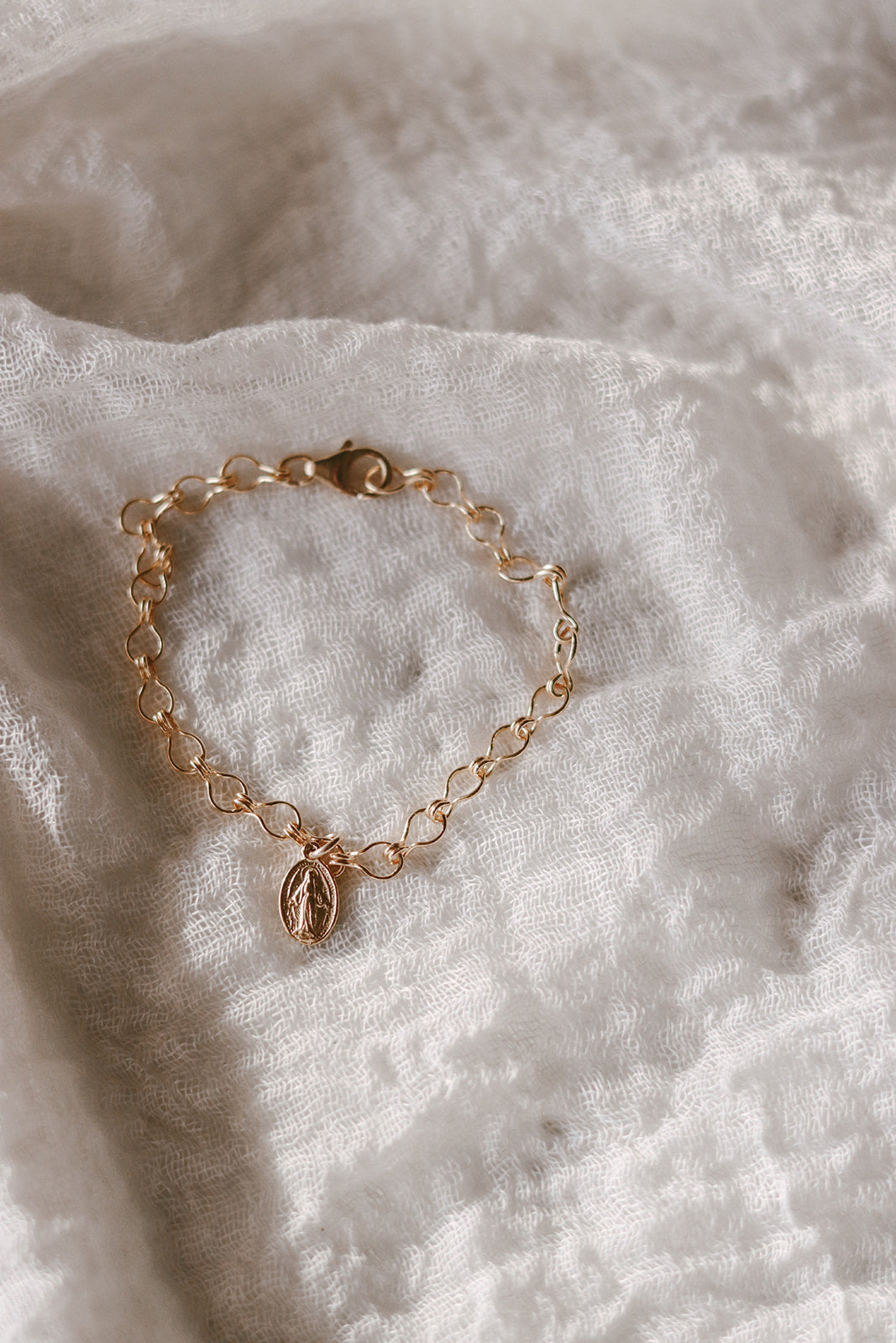 Gold-tone bracelet with oval medal charm and linked chain with clasp end