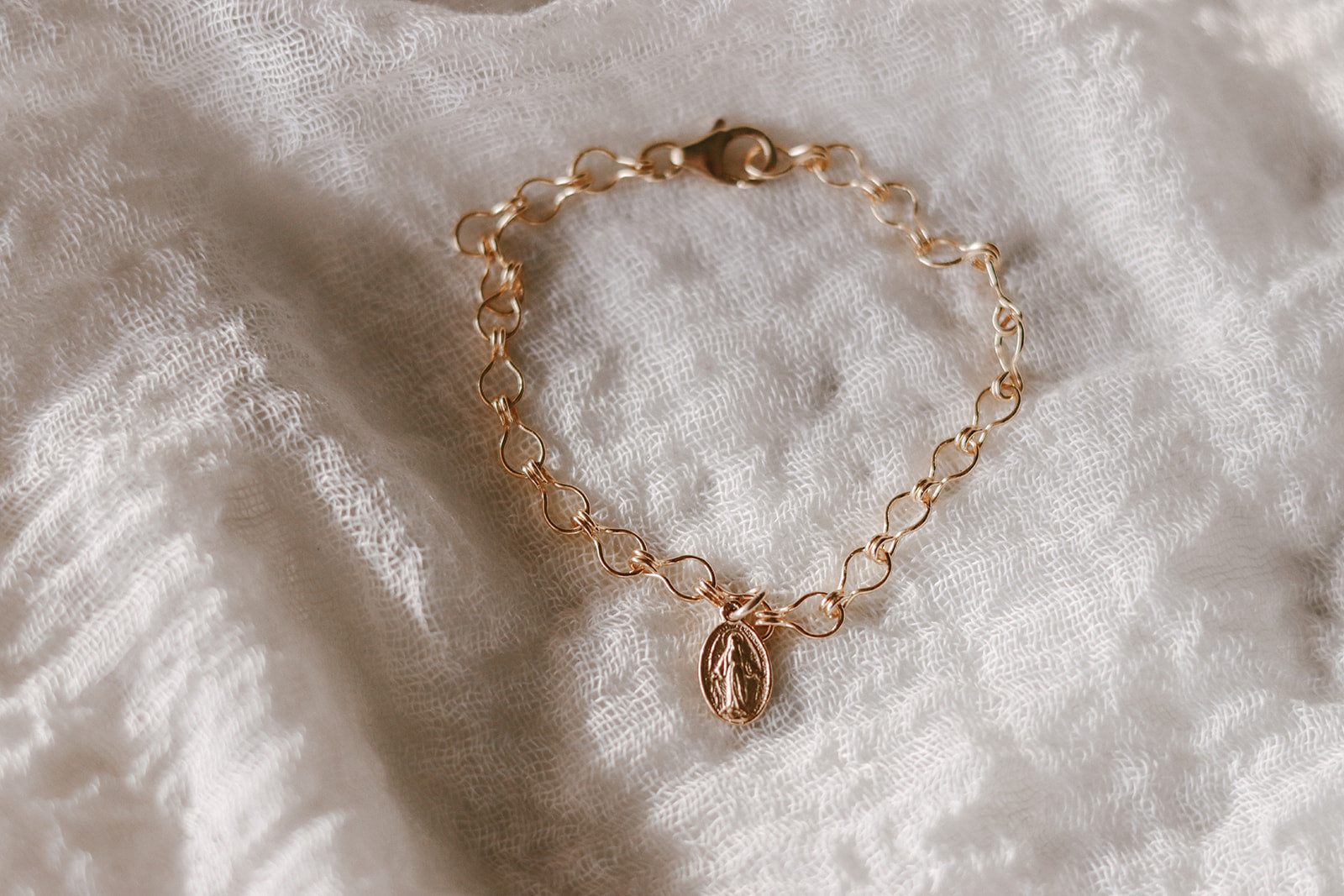 Gold-tone medal bracelet with circular chain links and small dangling charm