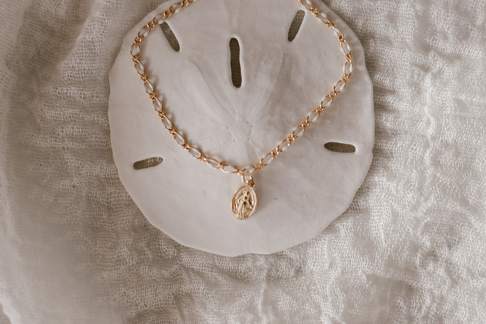 Close view of Miraculous Medal bracelet with gold charm on white backing