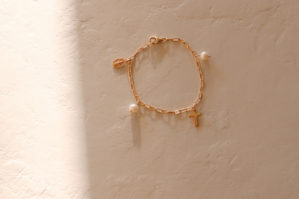 Gold link bracelet with pearl beads and a small cross charm