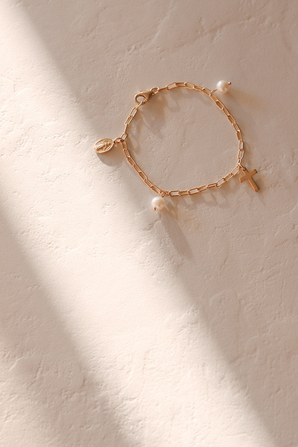 Gold-tone beaded bracelet with cross charm and white pearl drop accents