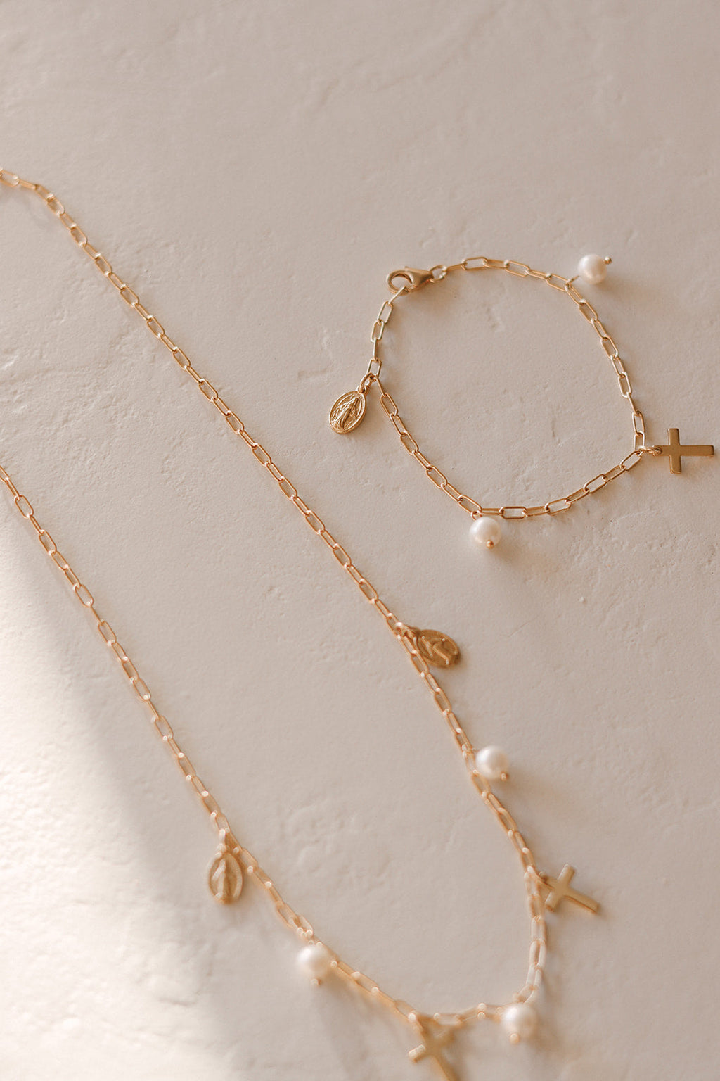 Gold-tone beaded bracelets with cross charms and white pearl drops