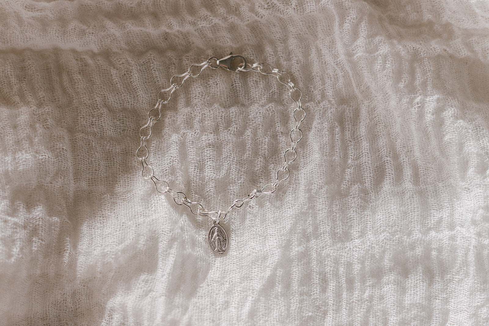 Sterling silver charm bracelet with clasp, oval Marian medallion pendant, and linked chain