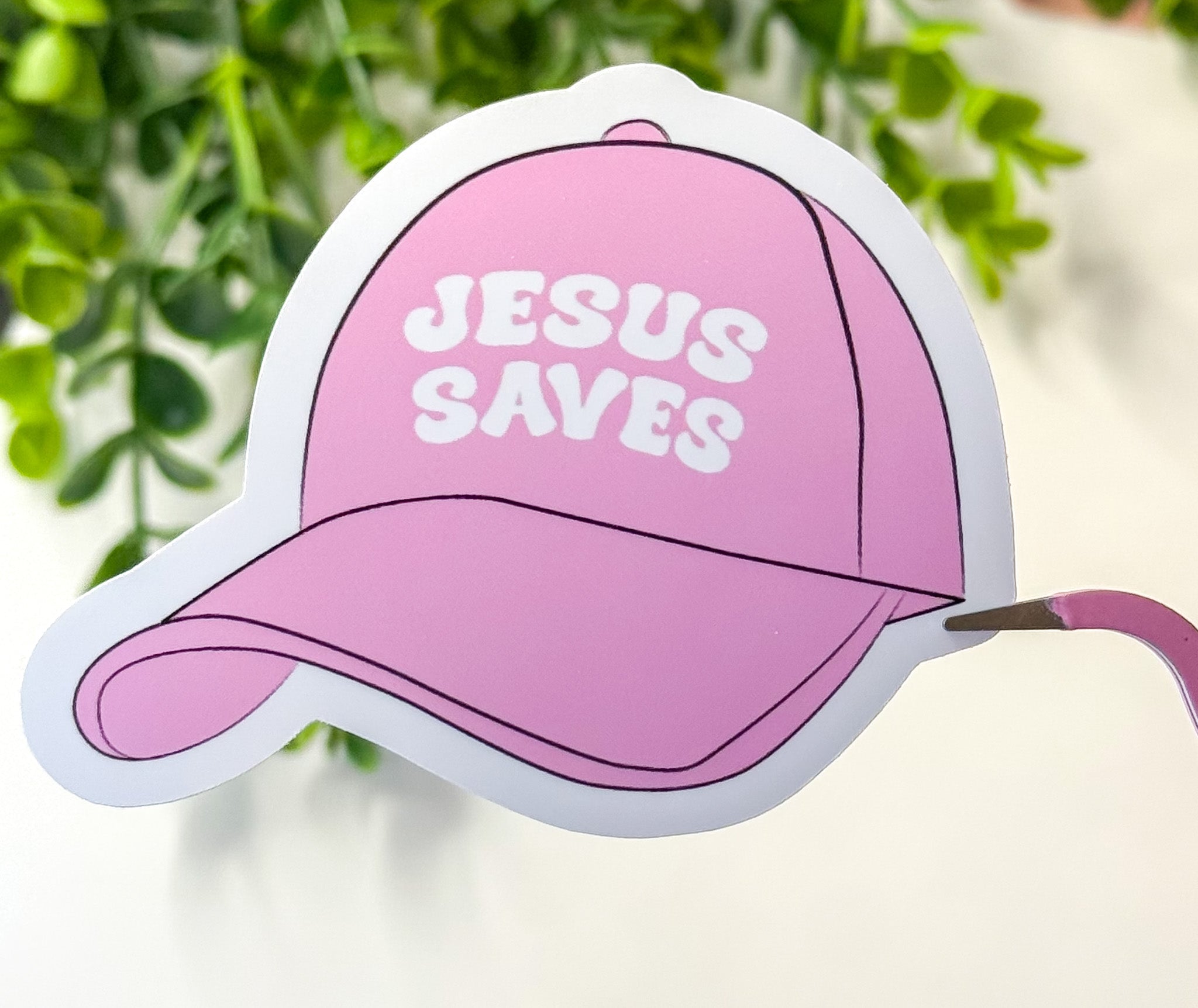 Pink cap-shaped sticker with 'JESUS SAVES' lettering
