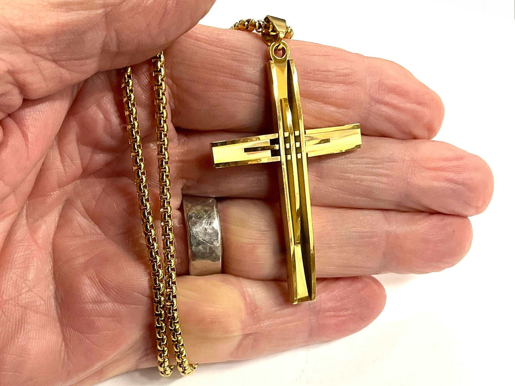 Gold-tone crucifix necklace with large cross pendant held in hand