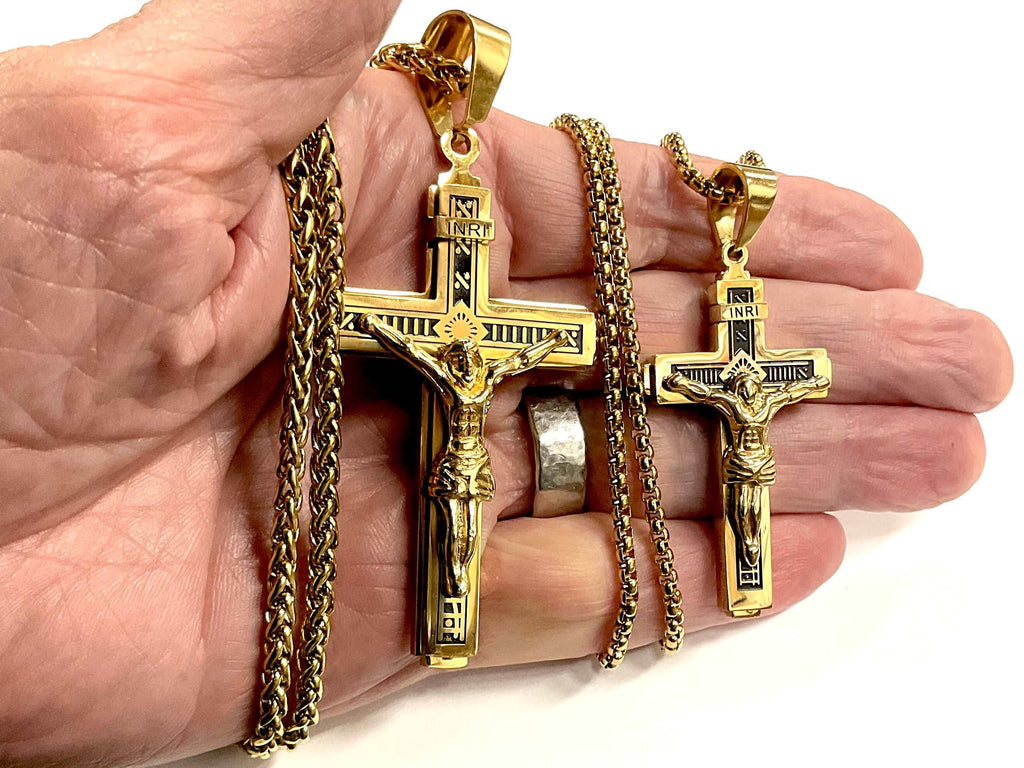 Gold cross crucifix necklace held in hand, linked chain and pendant