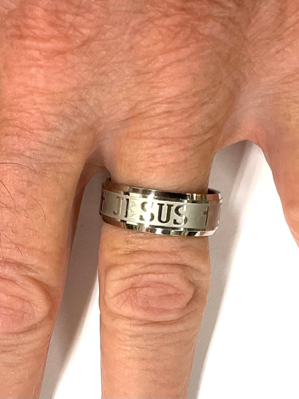 Wide silver stainless steel ring with cross and JESUS lettering on finger