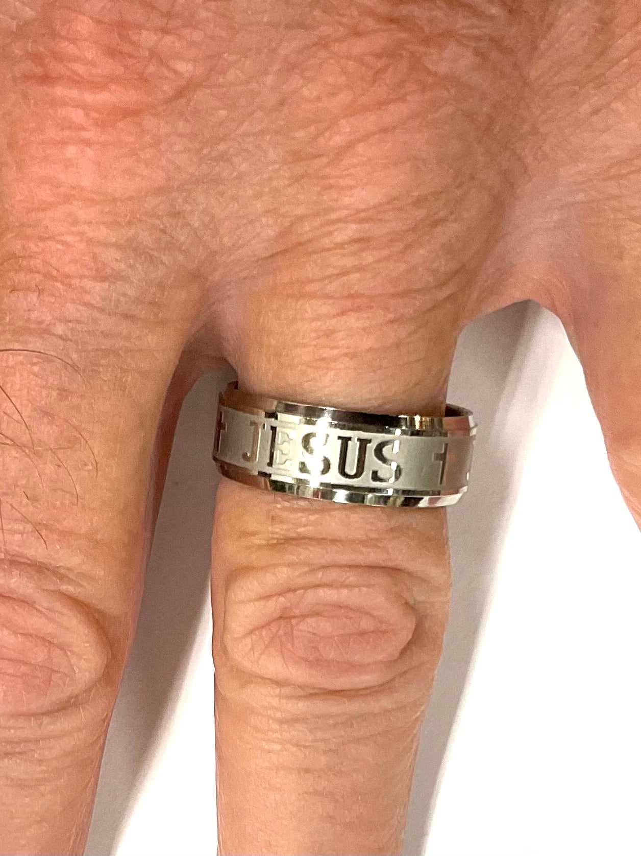 Wide silver stainless steel ring with cross and JESUS lettering on finger