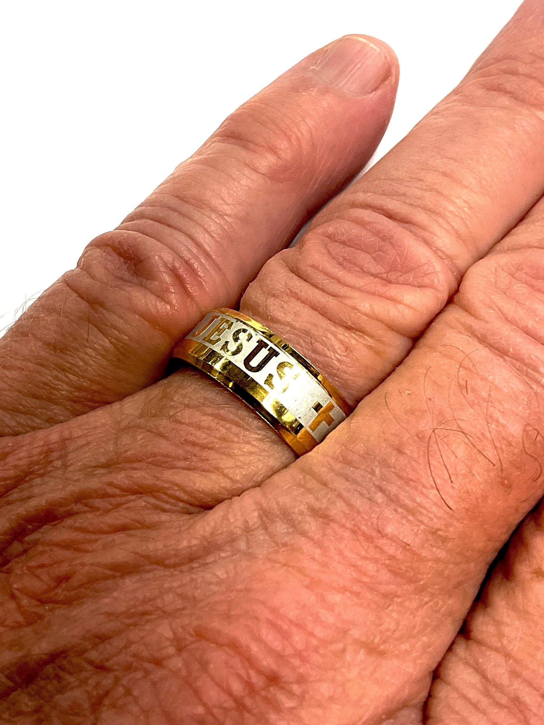 Gold wide ring with 'JE US' engraving on fingers