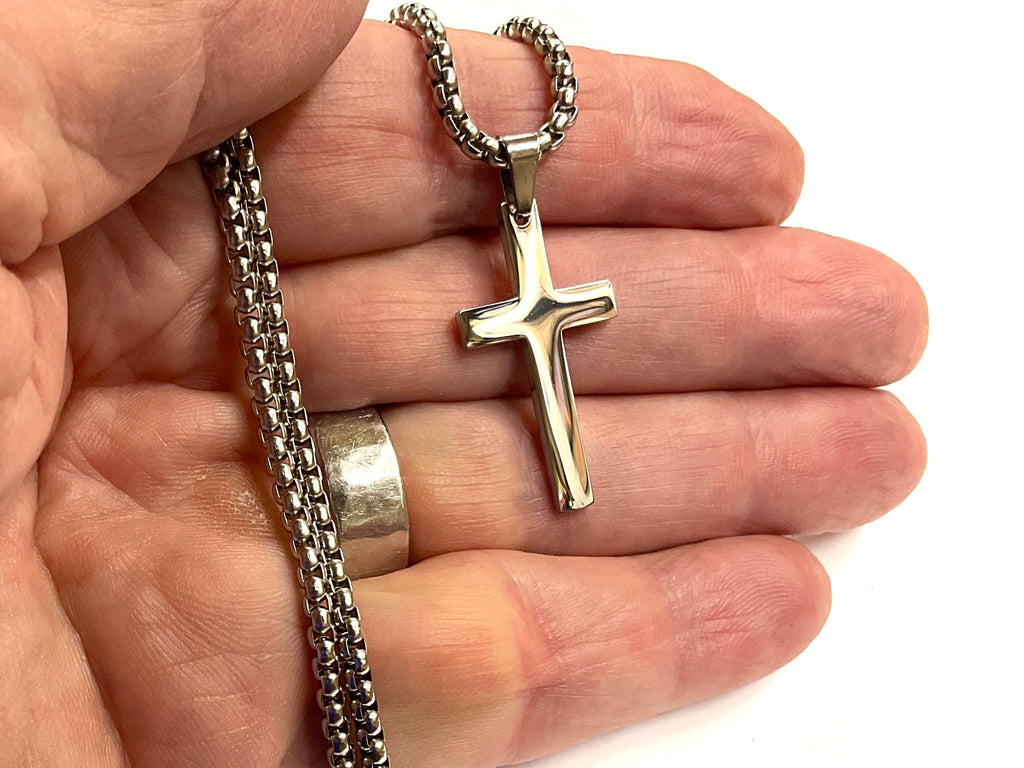 Cross pendant necklace held in hand with silver chain