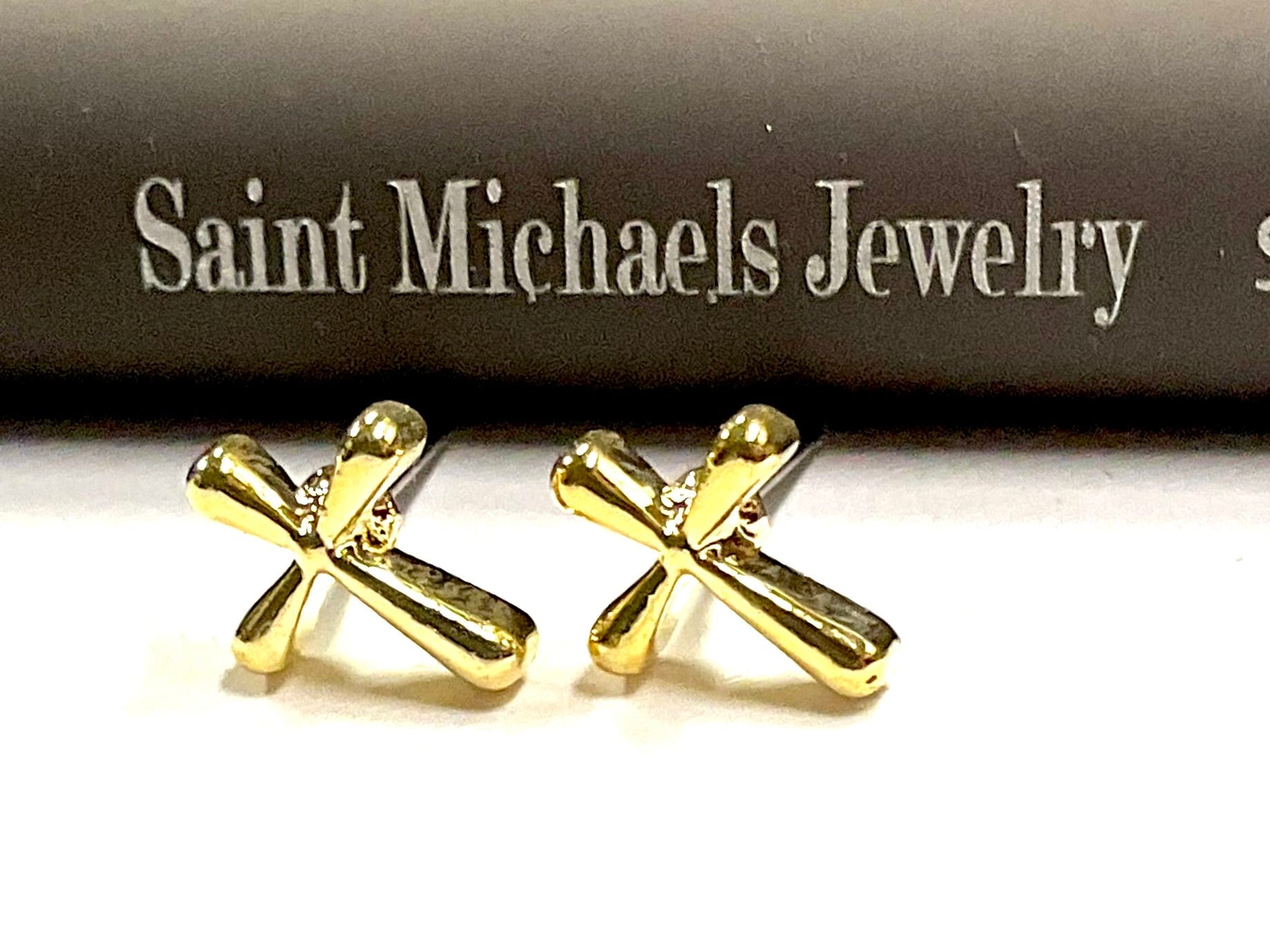 Gold cross stud earrings with modern flowing curved cross detailing