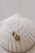 Gold-tone pendant necklace with oval medal charm and starburst charm on chain
