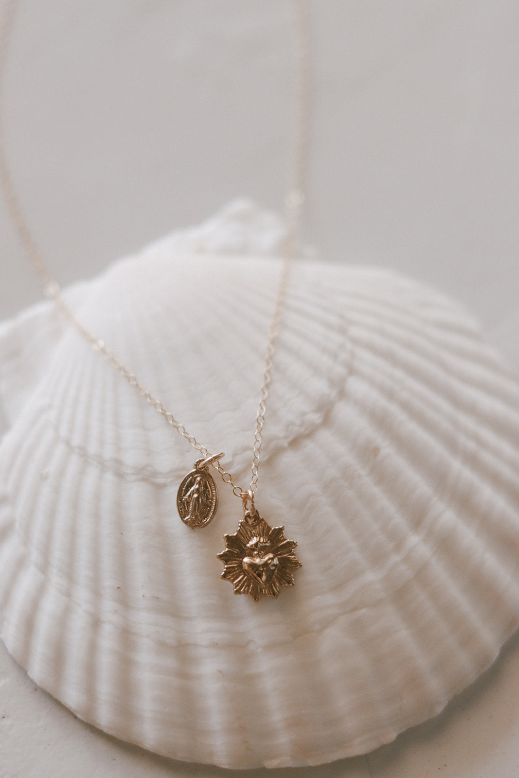 Gold-tone pendant necklace with oval medal charm and starburst charm on chain