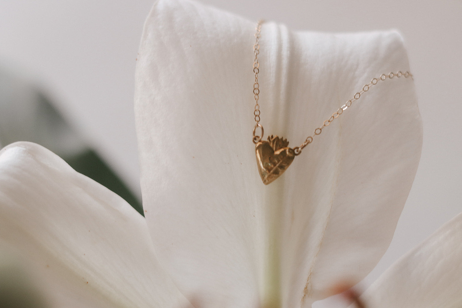 Gold heart pendant necklace with fine chain, small floral detail on pendant