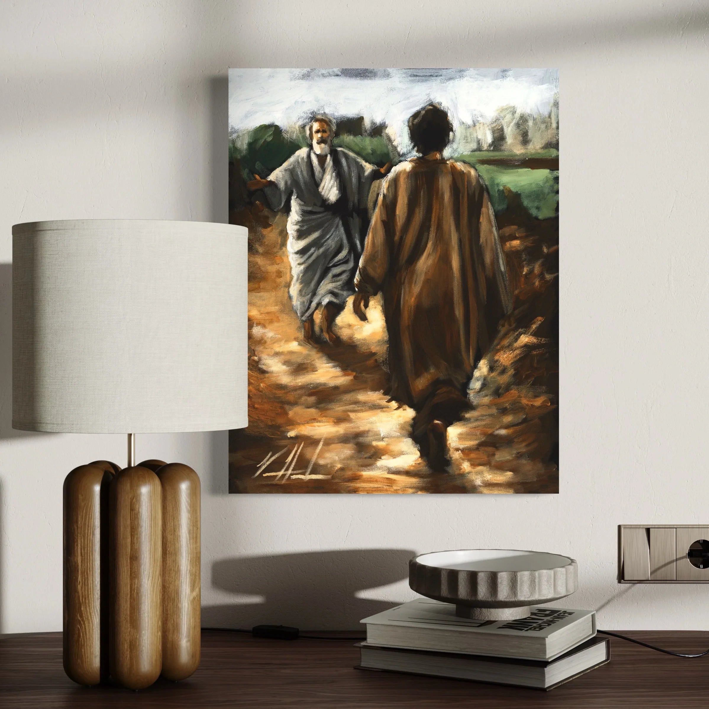 Framed artwork print of two men walking displayed above a sideboard and lamp