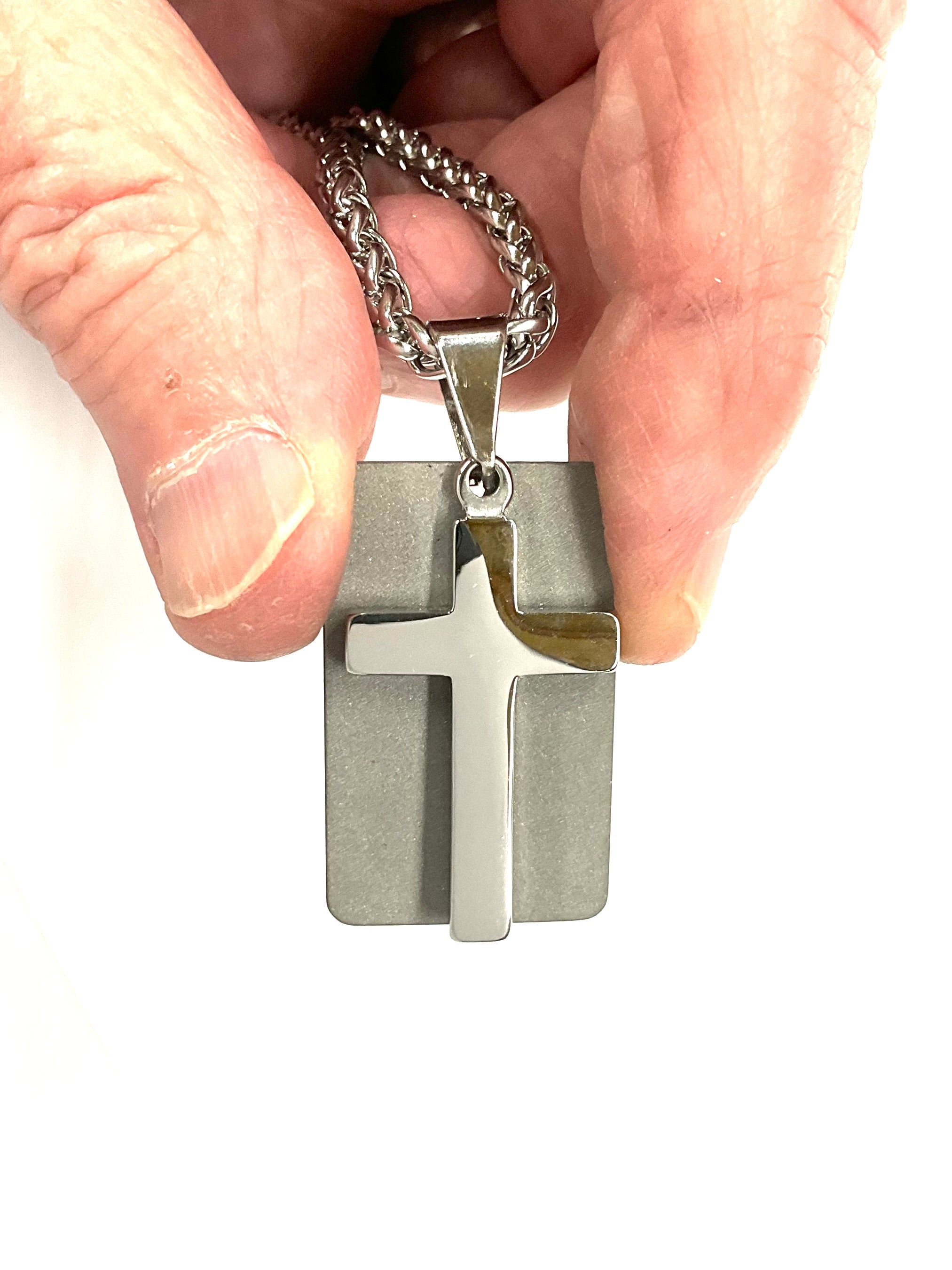 Silver cross dog tag necklace pendant on chain in open palm