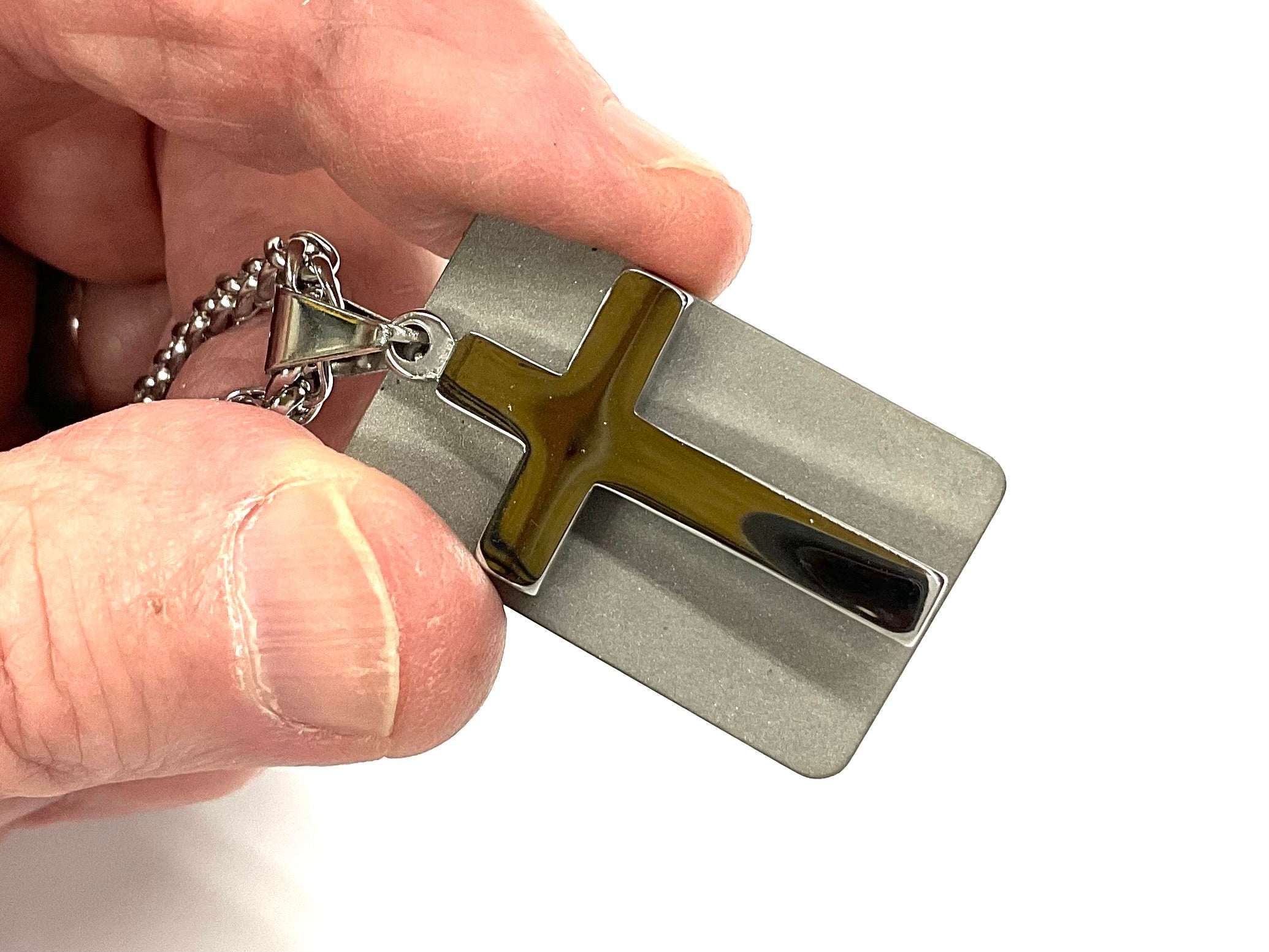 Silver cross dog tag necklace pendant close-up held with chain