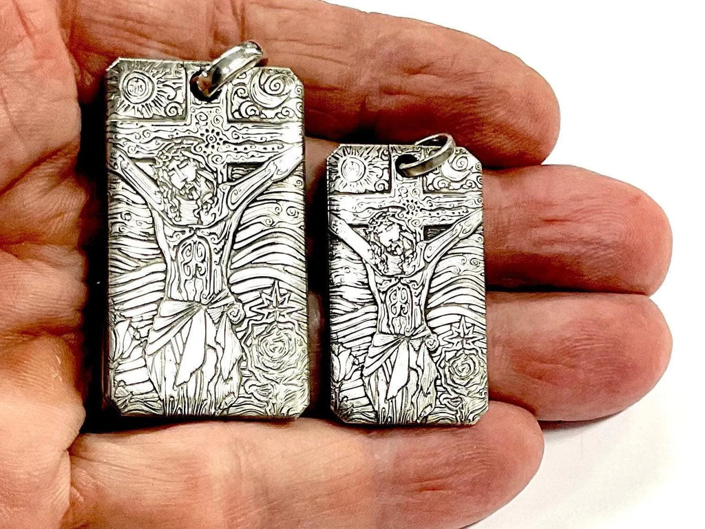 Sterling silver dog tag pendants held in hand, engraved Jesus cross designs