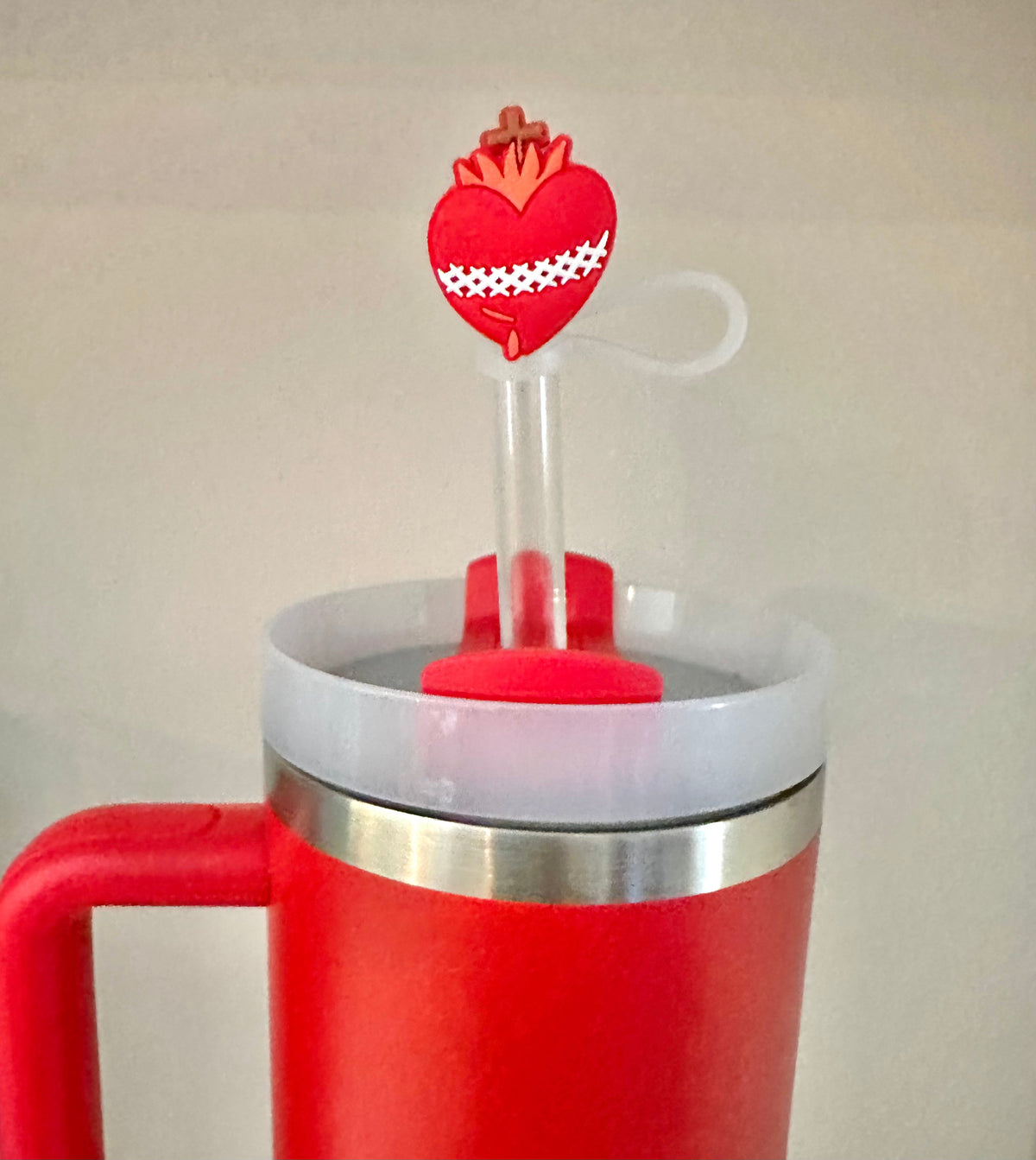Close-up of red heart straw topper with crown and white loop on a clear straw
