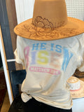 White crewneck T-shirt with “He is Risen” back graphic in pink and blue