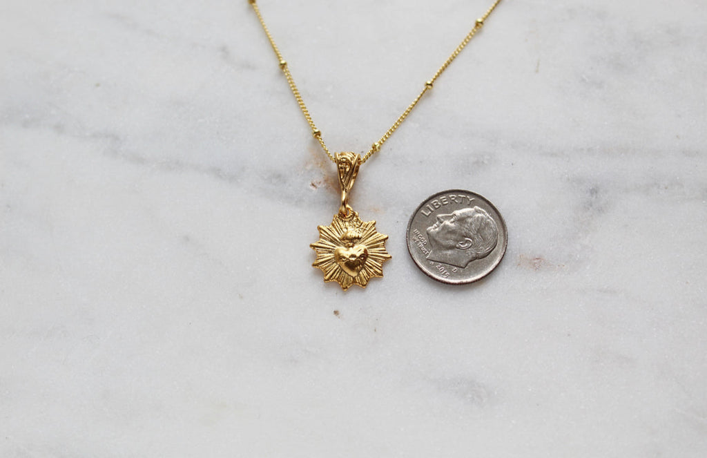 Scalloped necklace with gold sunburst pendant and small-link chain, front view