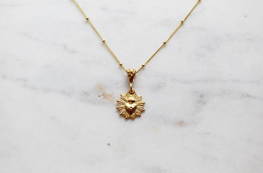 Gold-tone scalloped heart charm necklace with a single small medallion pendant