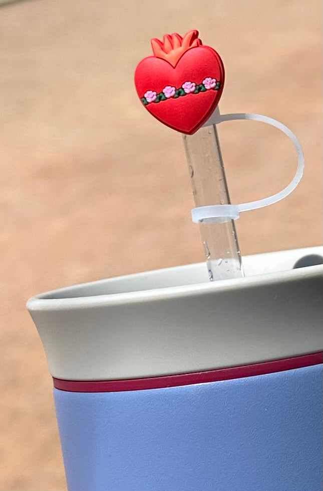 Red heart straw topper with crown and floral details on a clear straw in a blue cup