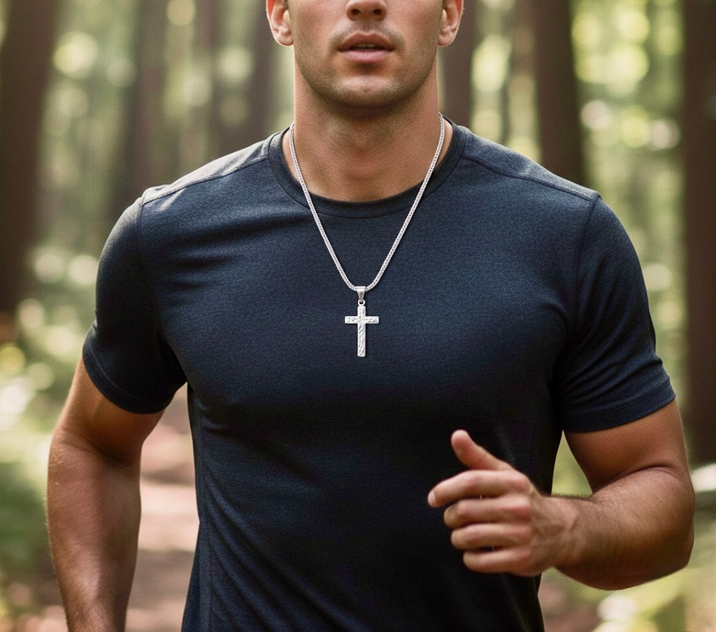 Silver cross pendant necklace worn by a man, chain hanging at chest