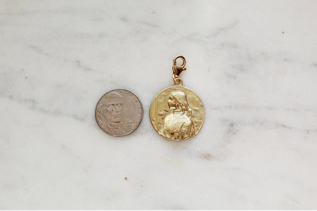 St. Joan of Arc medallion pendant in gold, shown beside a coin for scale