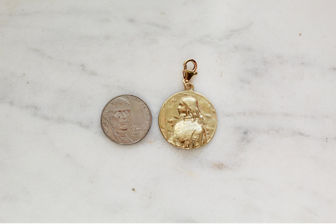 St. Joan of Arc medallion pendant in gold, shown beside a coin for scale