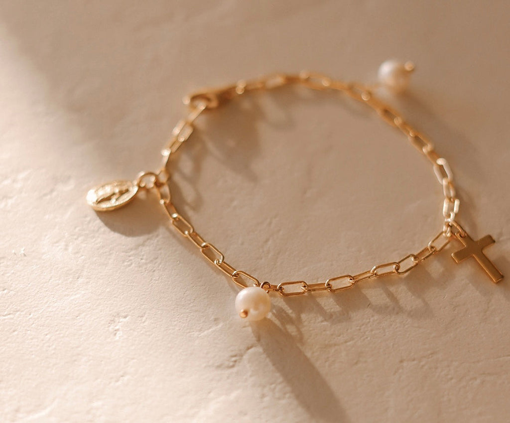 Gold link bracelet with white pearl beads and a small cross charm