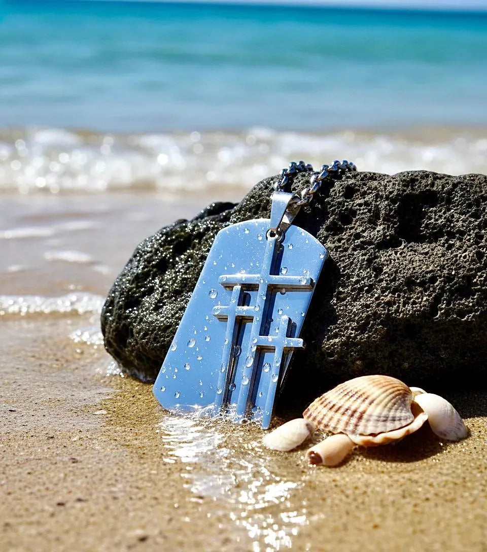 Triple cross dog tag pendant on a chain near beach sand and waves