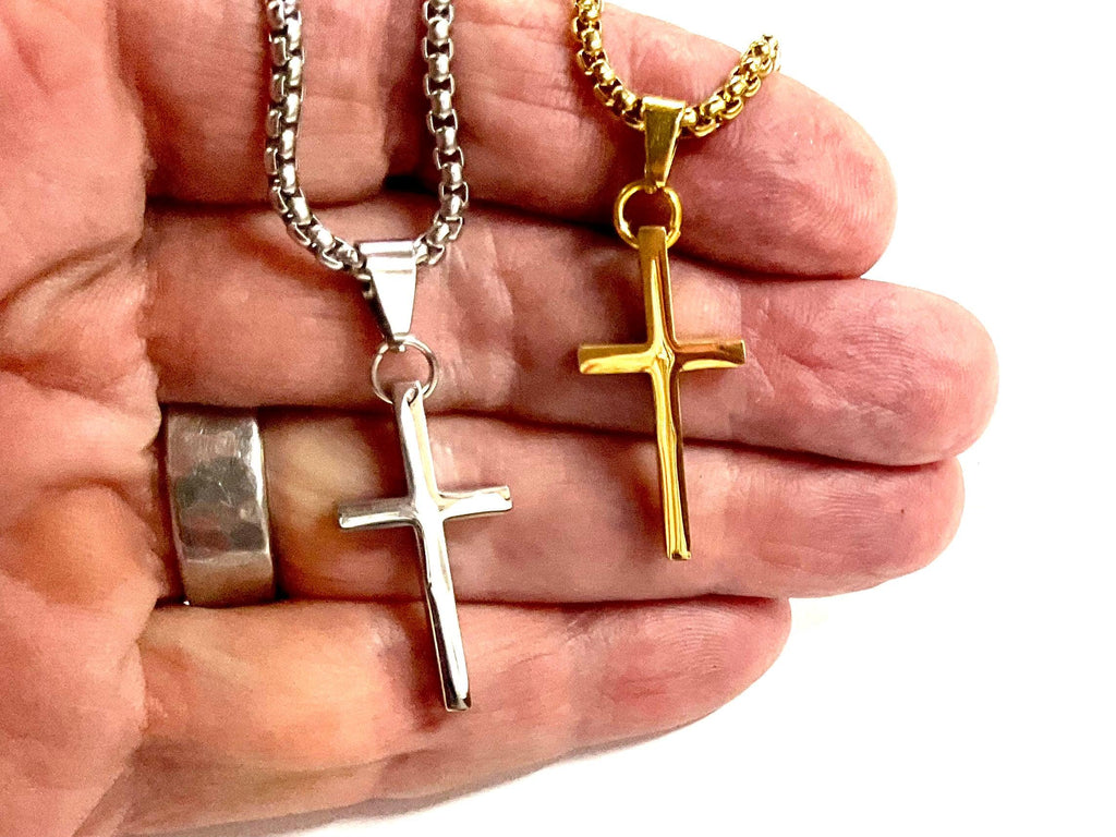 Silver and gold cross pendant necklaces in hand