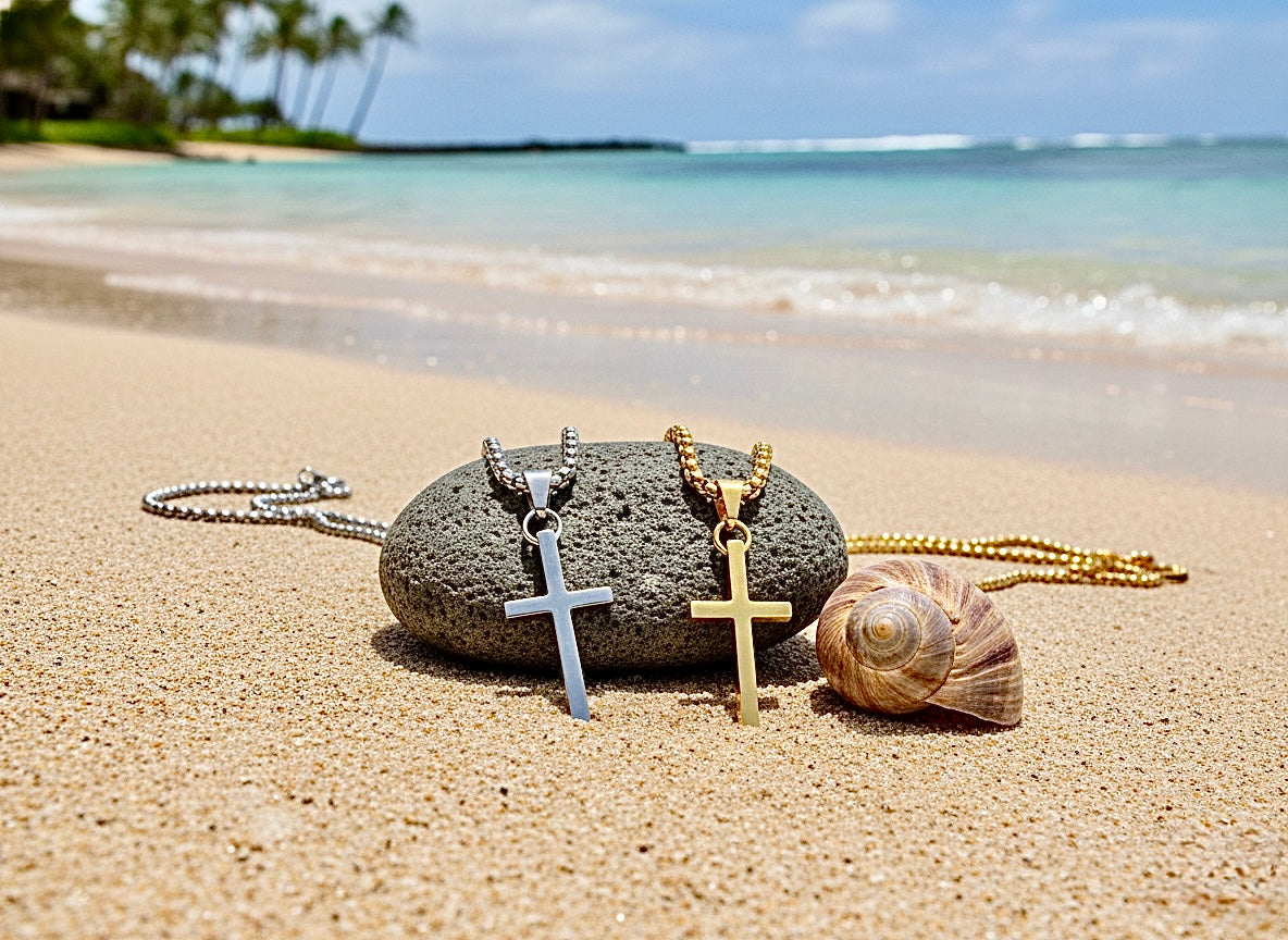 Cross pendant necklaces resting on beach sand and shells
