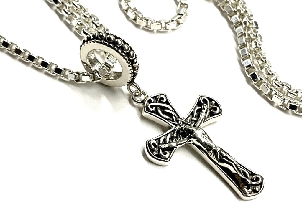Celtic cross crucifix pendant with ornate details and silver chain links.