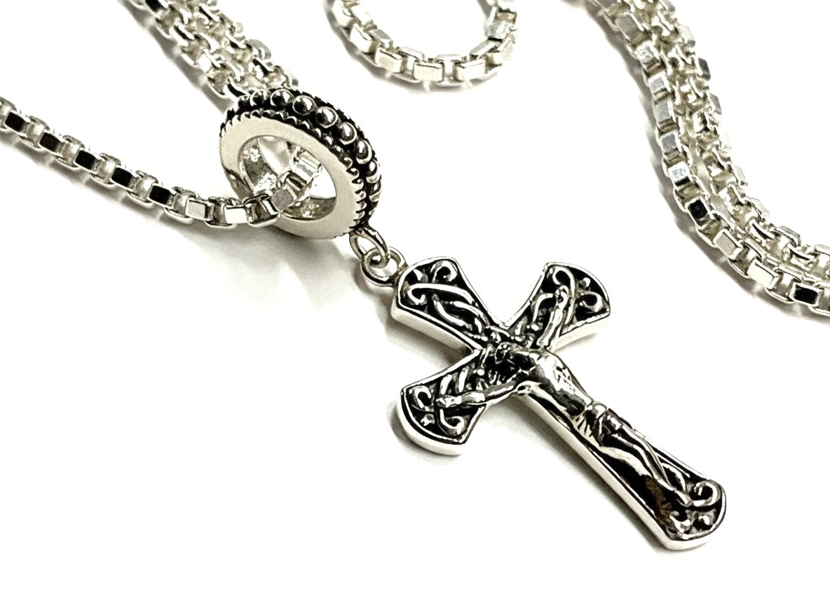 Celtic cross crucifix pendant with ornate details and silver chain links.