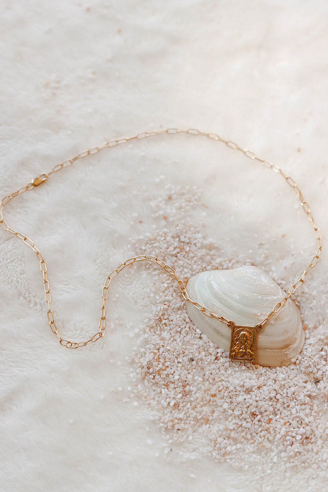 Scapular charm necklace with gold-tone chain and square charm on white stone