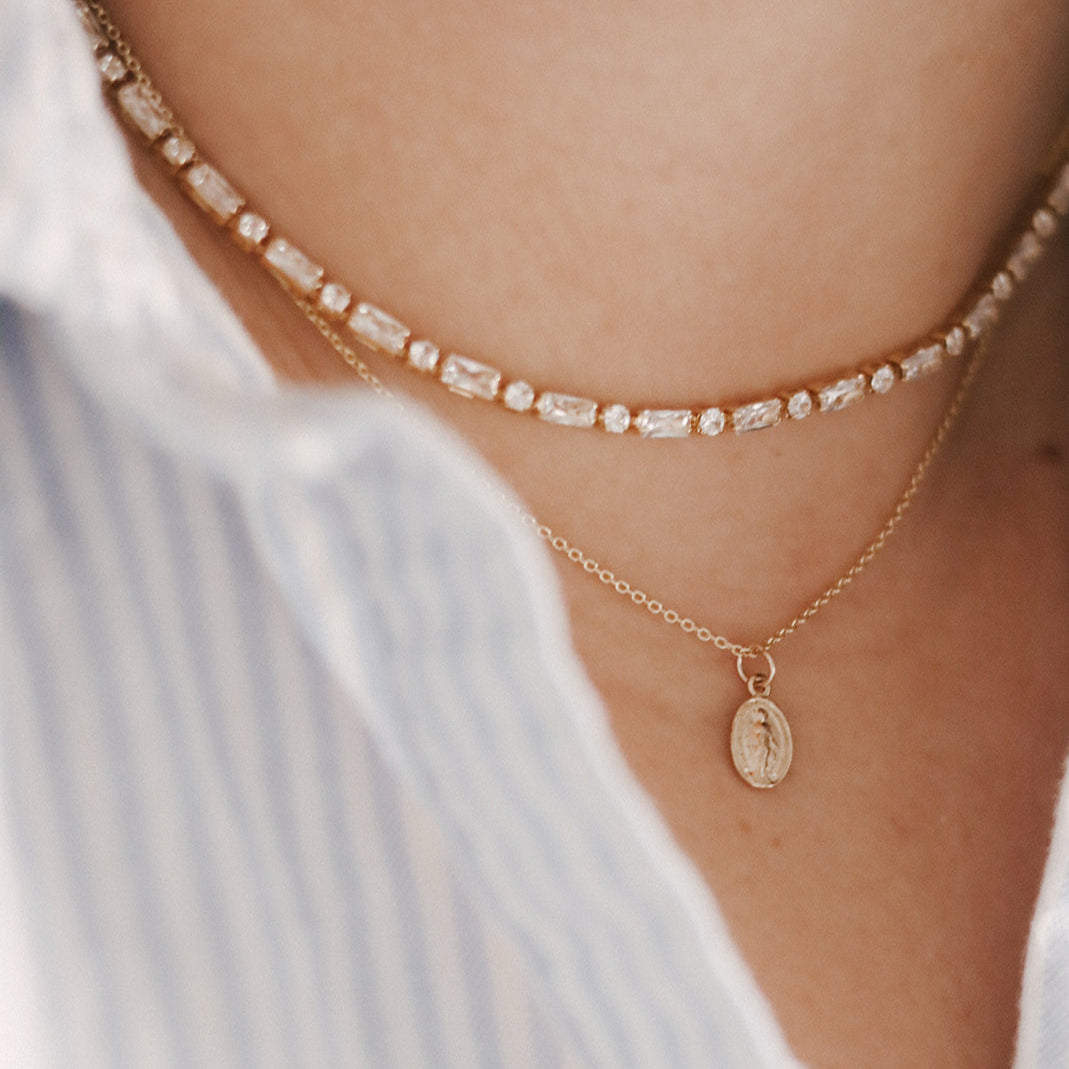 14k gold medal necklace with small oval pendant and thin chain layered look