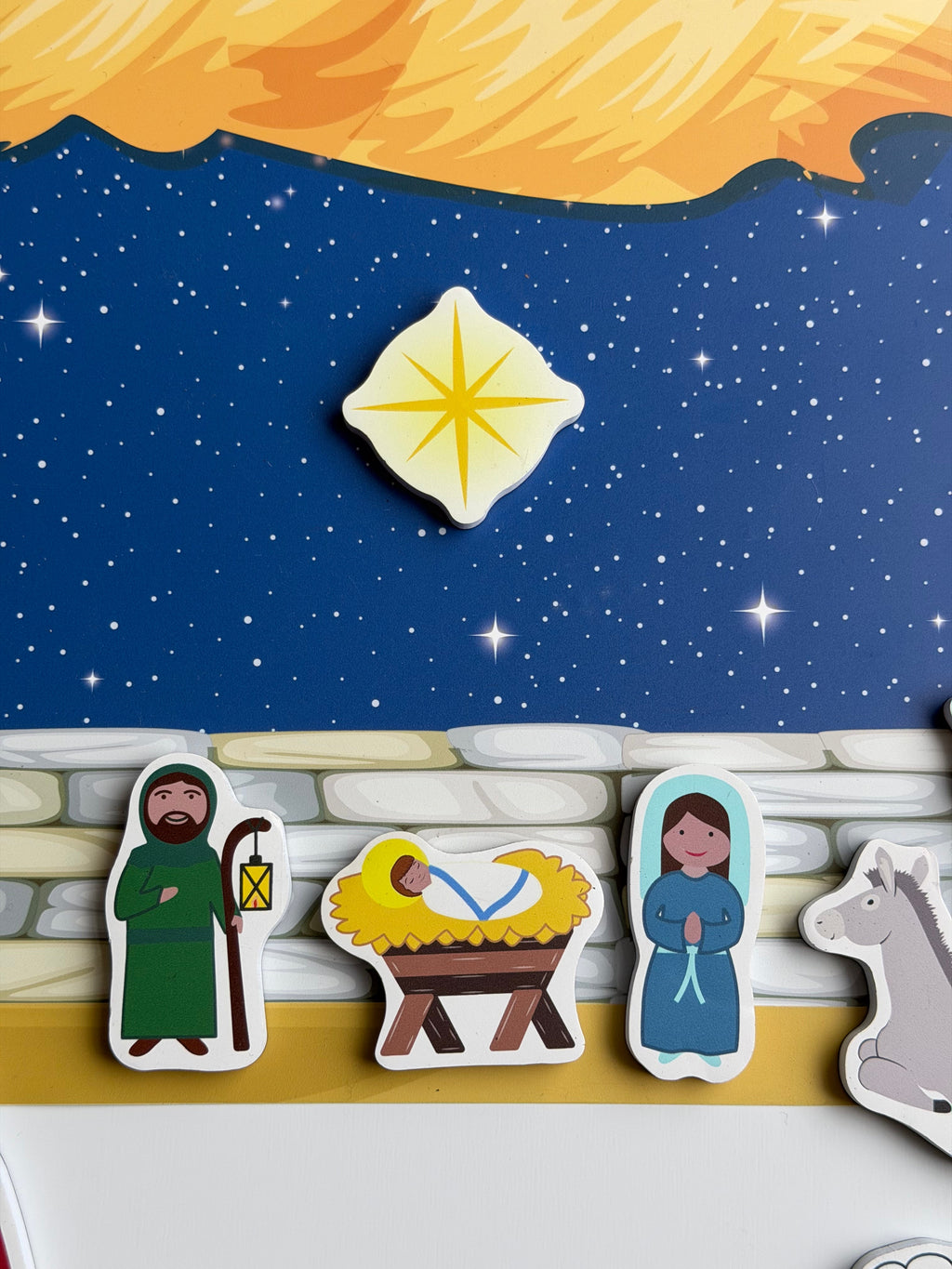 Nativity magnet set close-up: gold star magnet over manger with shepherd and animal