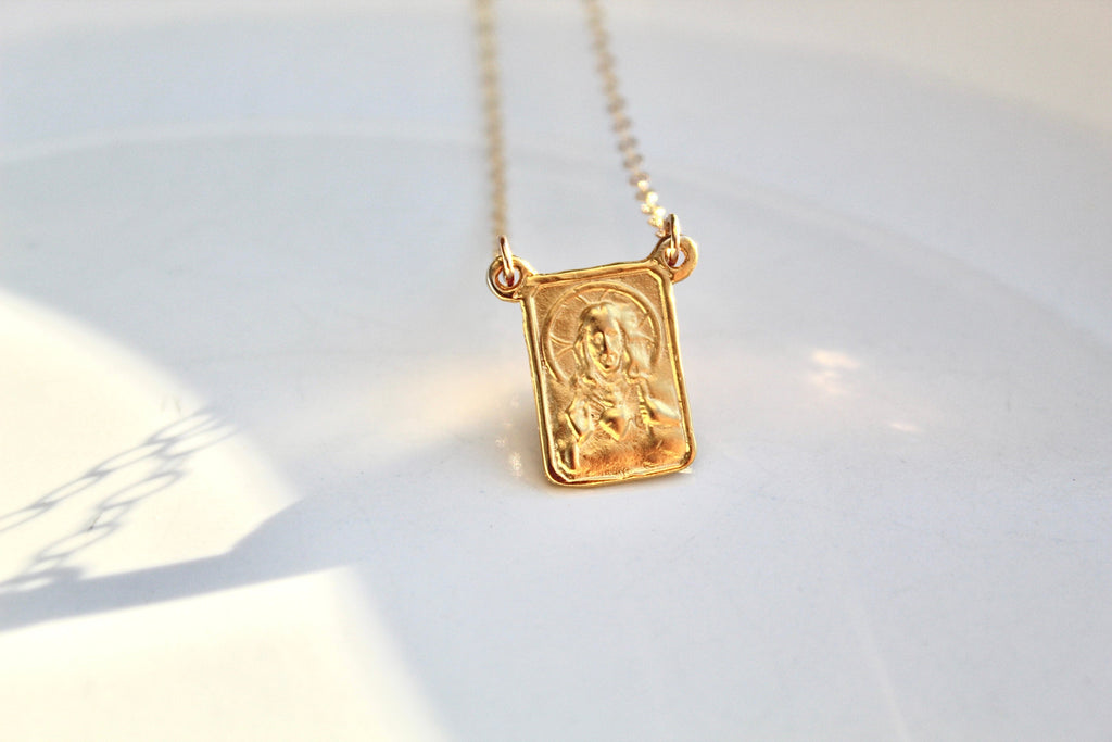 Gold-tone scapular pendant necklace with square charm on a fine chain, front view.