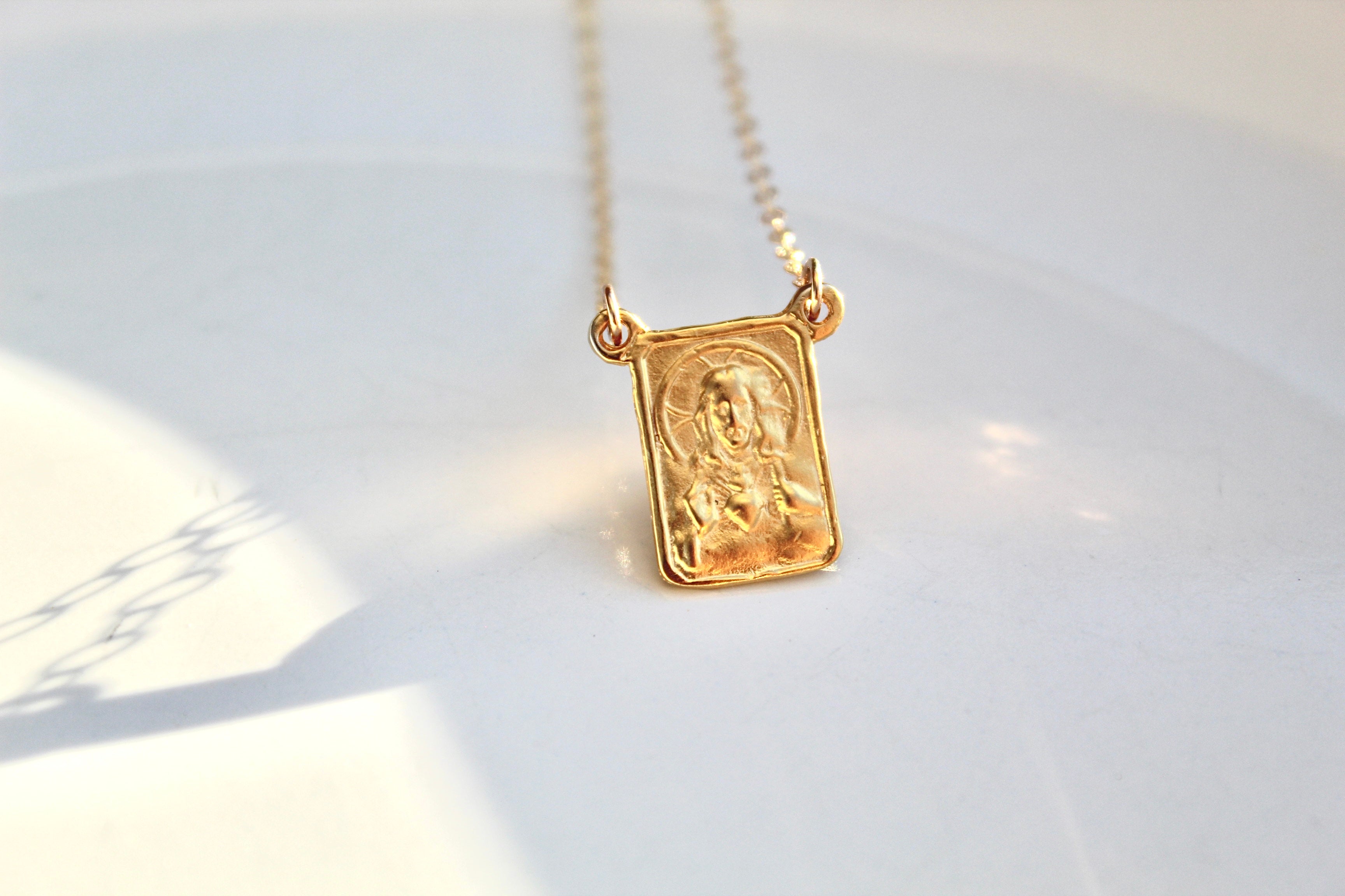Gold-tone scapular pendant necklace with square charm on a fine chain, front view.