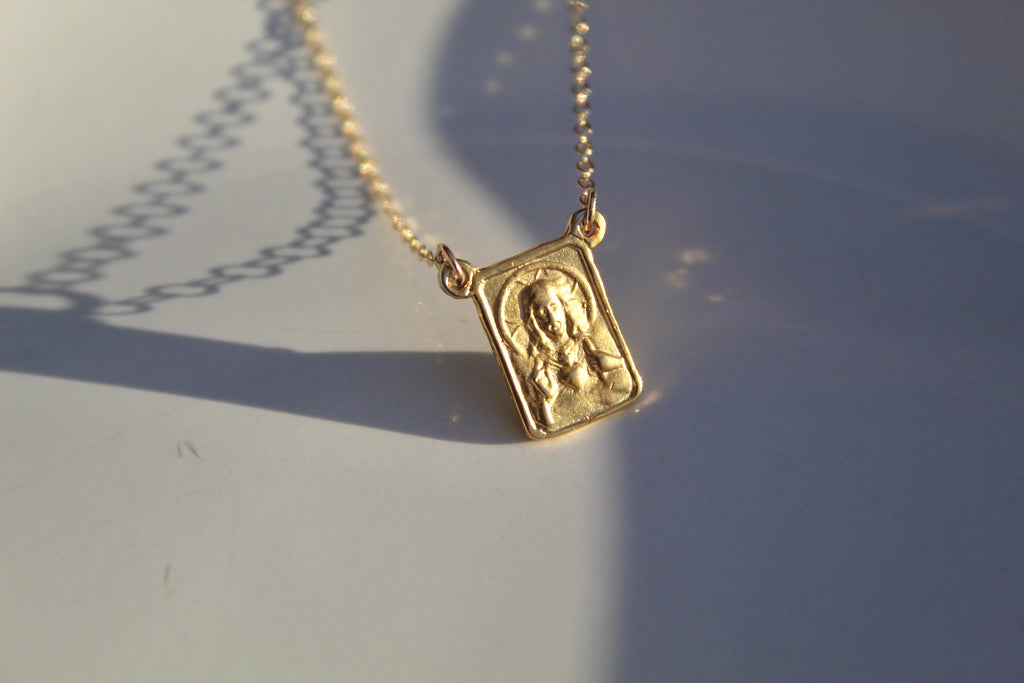 Gold scapular necklace with detailed rectangular pendant on chain