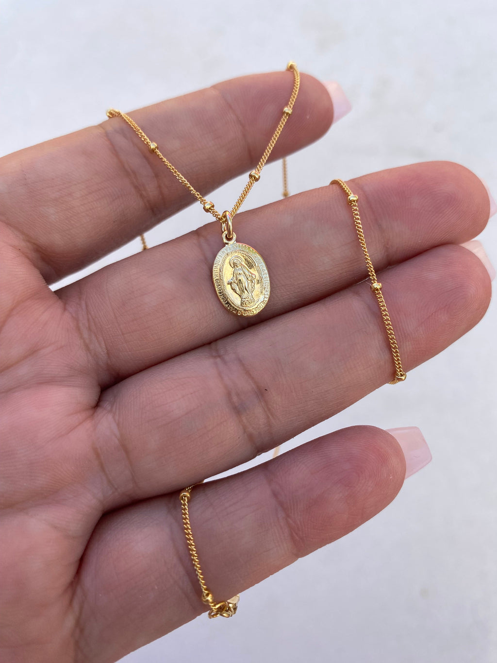 Gold-tone medal necklace with oval pendant on a fine chain