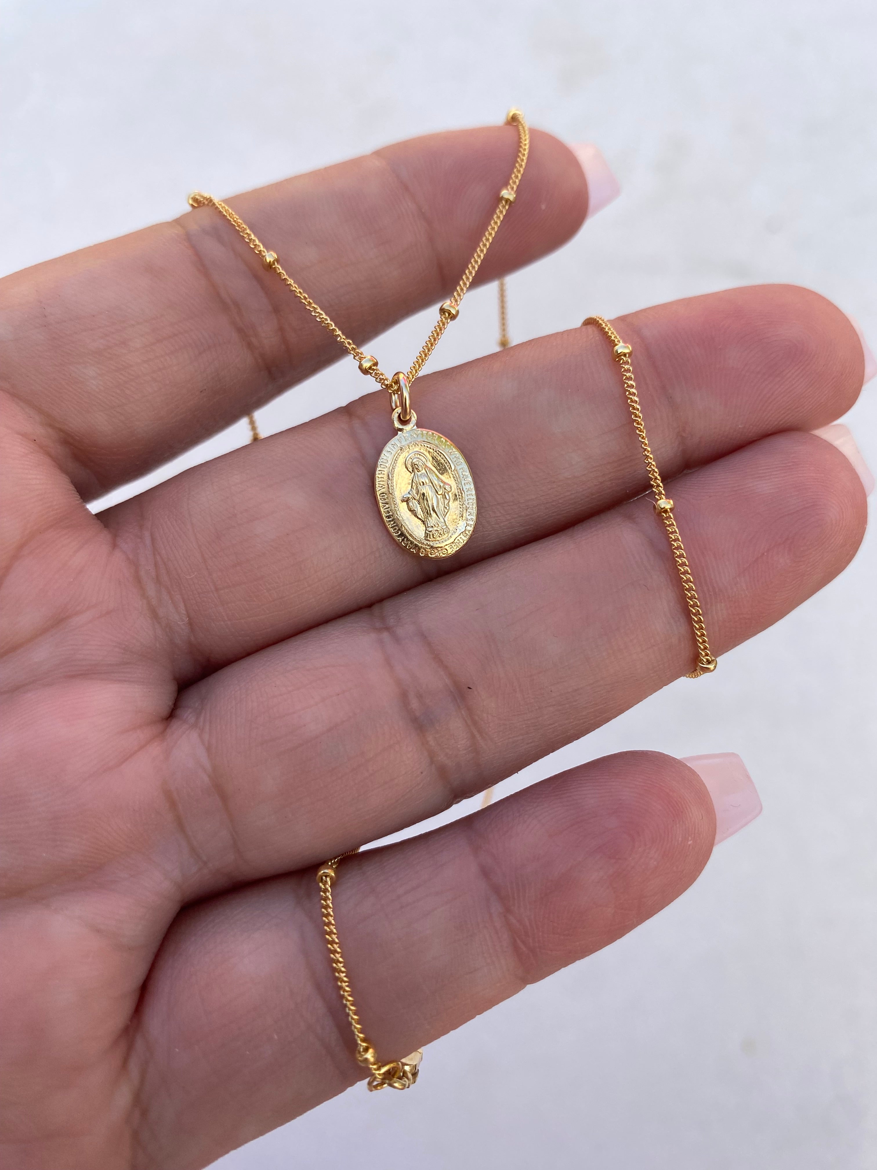 Gold-tone medal necklace with oval pendant on a fine chain