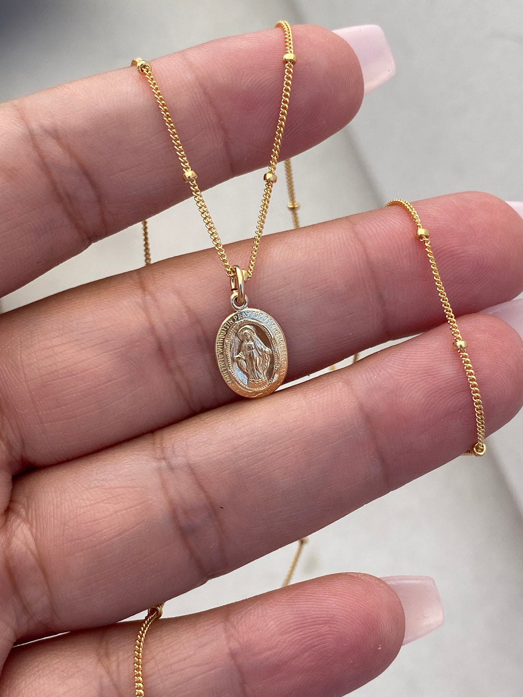 Gold-tone medal necklace with oval pendant on a fine chain